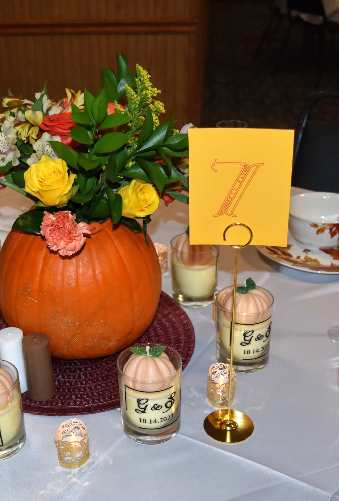An autumn tablescape with a pumpkin centrepiece, flowers and votive candles