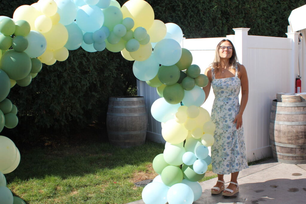 A green and cream balloon arch in a garden