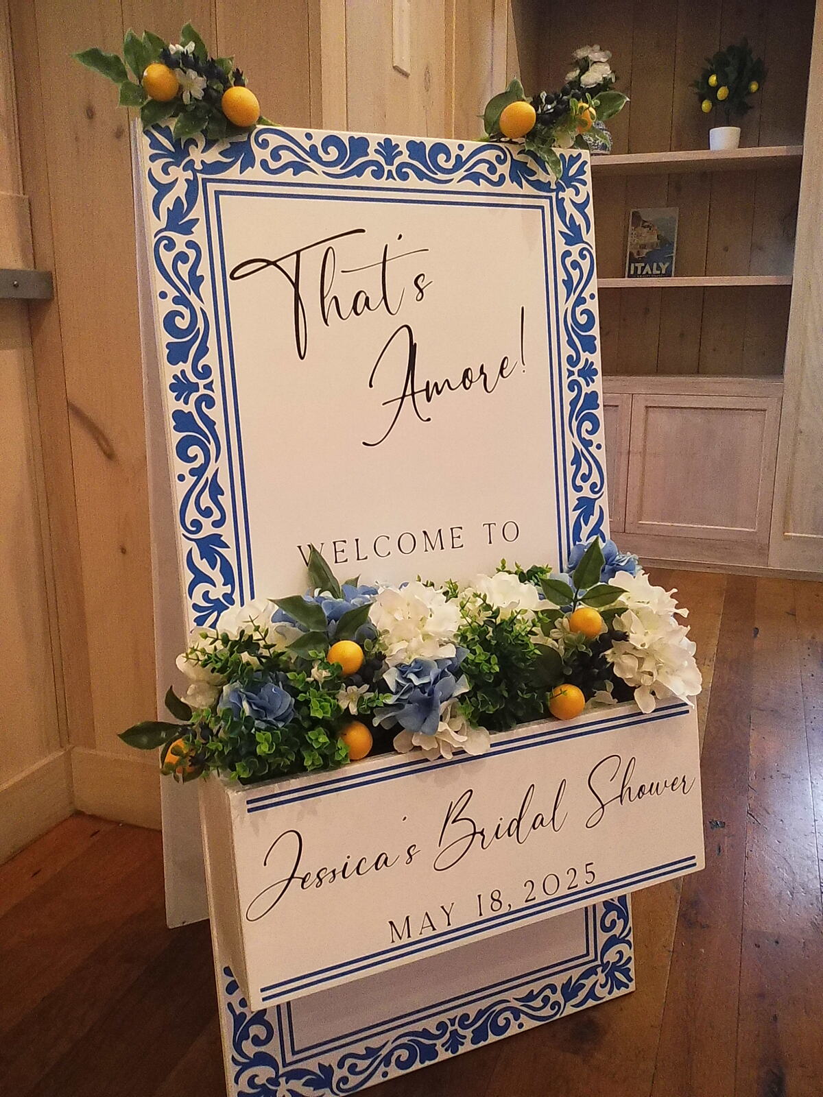 A bridal shower welcome sign in a blue tile frame with lemons and white flowers