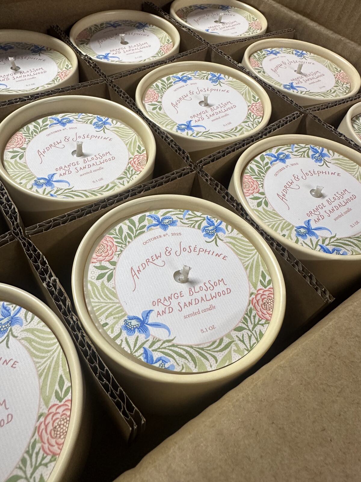 Candle tins with custom floral wedding labels packed in a box