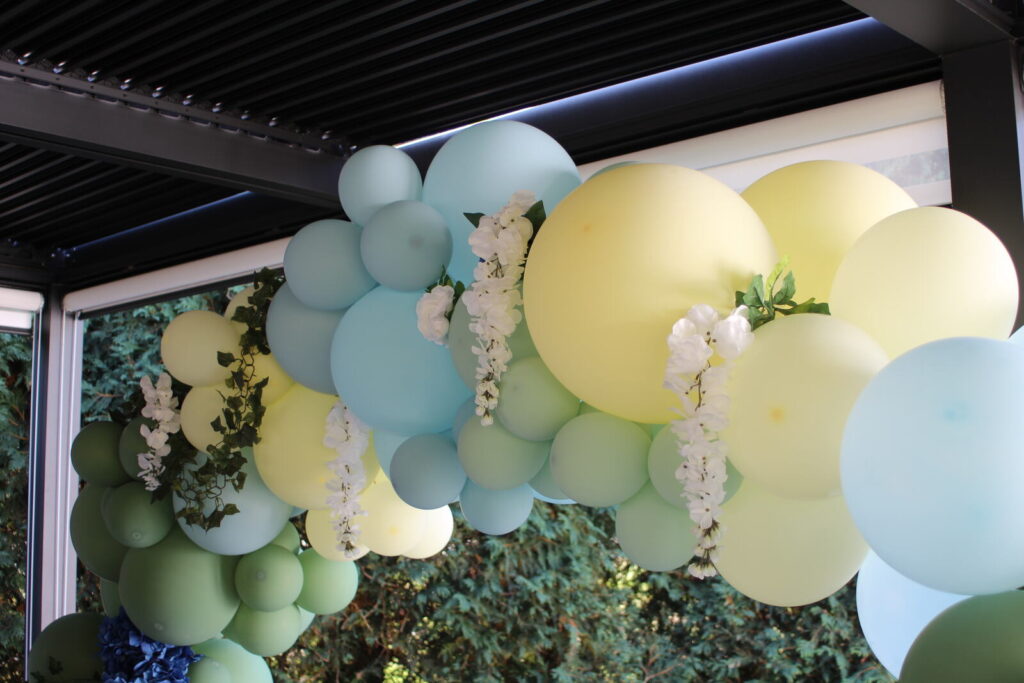 A green and cream balloon garland with trailing greenery