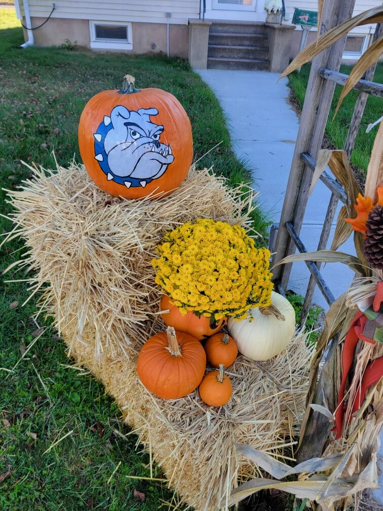 An autumn display of pumpkins, mums and cornstalks on a hay bale