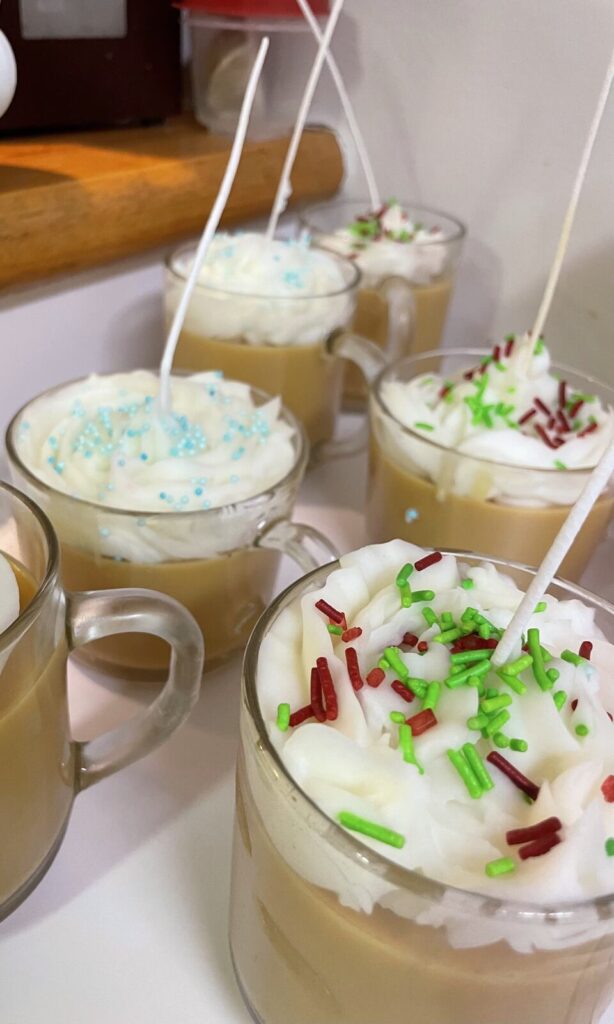 Candles poured into glass mugs to look like hot cocoa, topped with whipped wax and red and green sprinkles