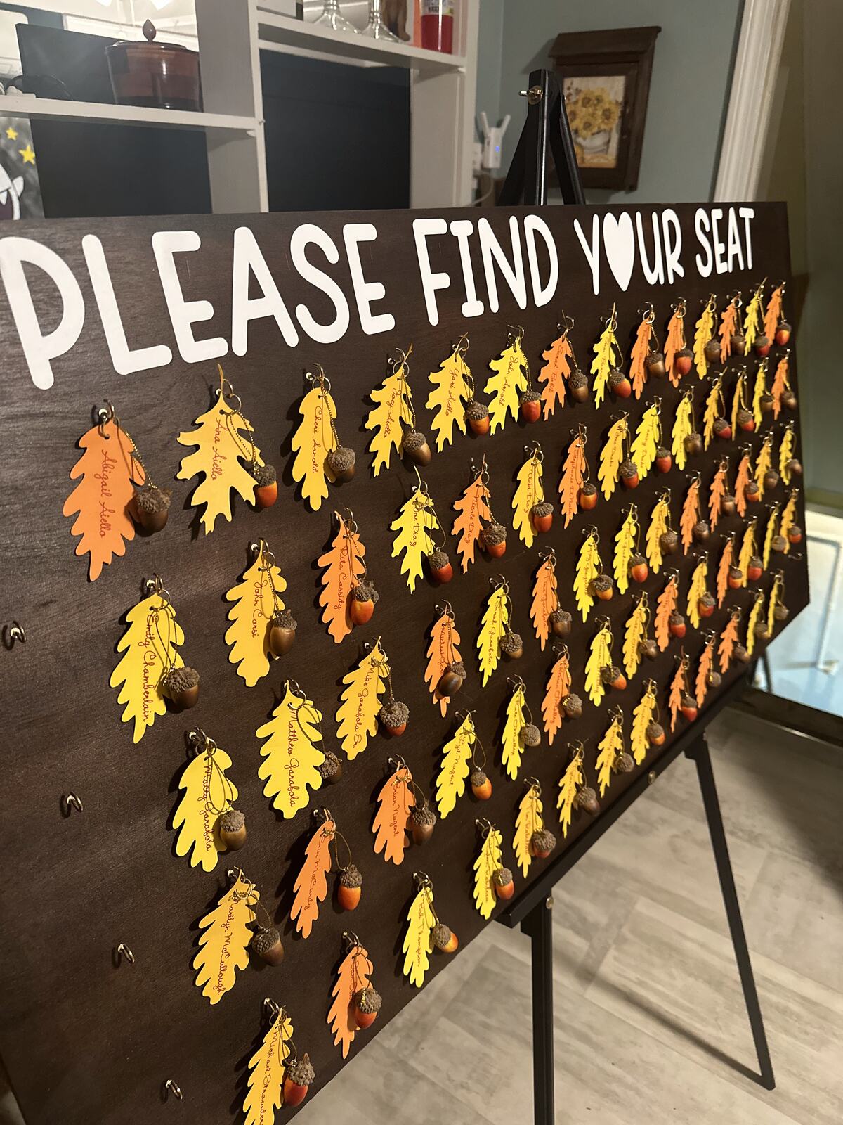 A seating chart made of cut paper autumn leaves on a dark board