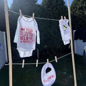 Decorated baby onesies pegged along a clothesline at a shower