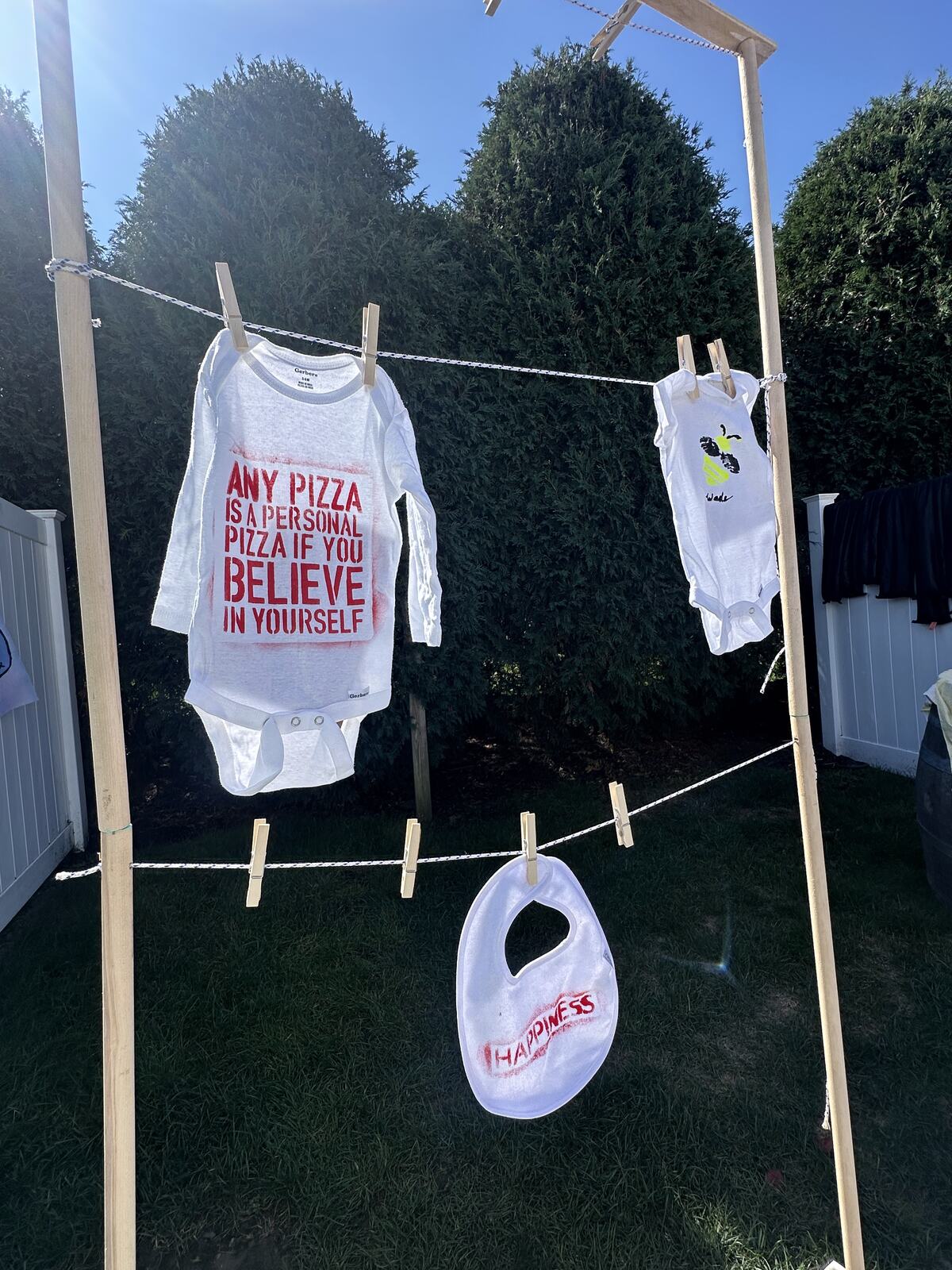 Decorated baby onesies pegged along a clothesline at a shower