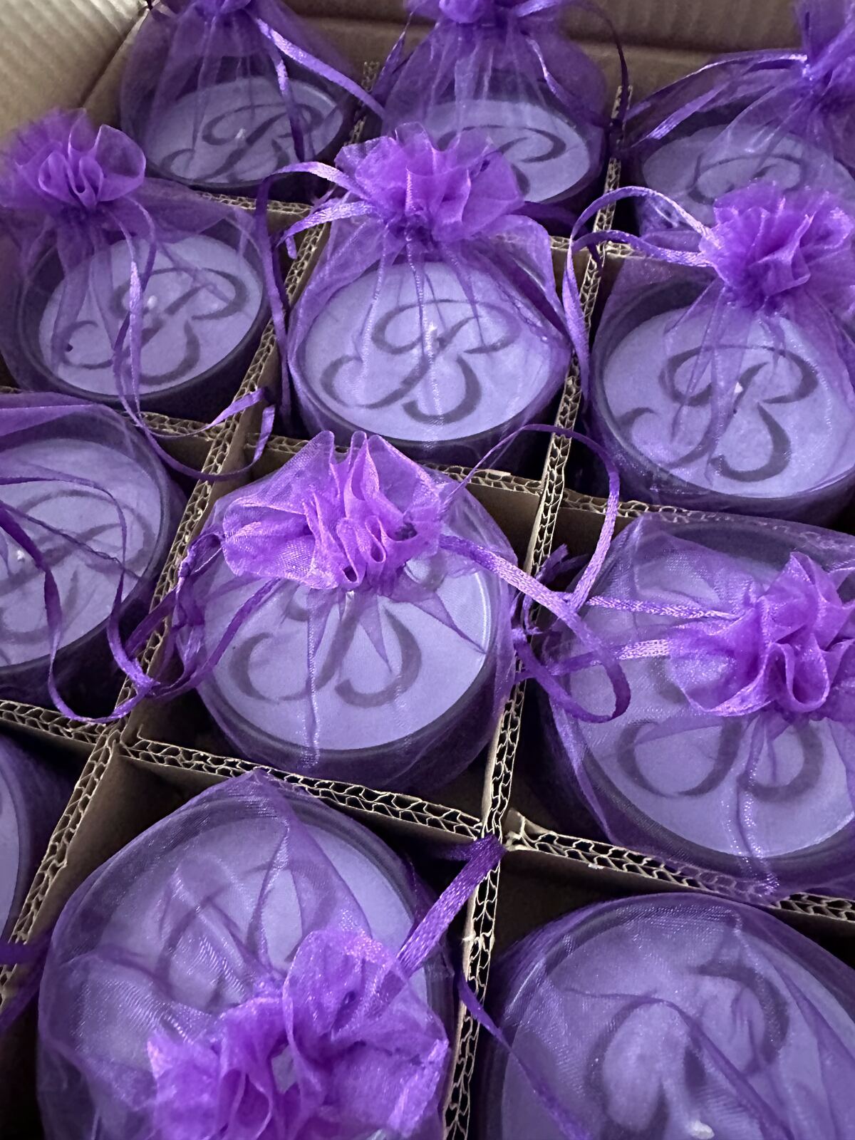 Monogrammed candle tins in purple organza favour bags