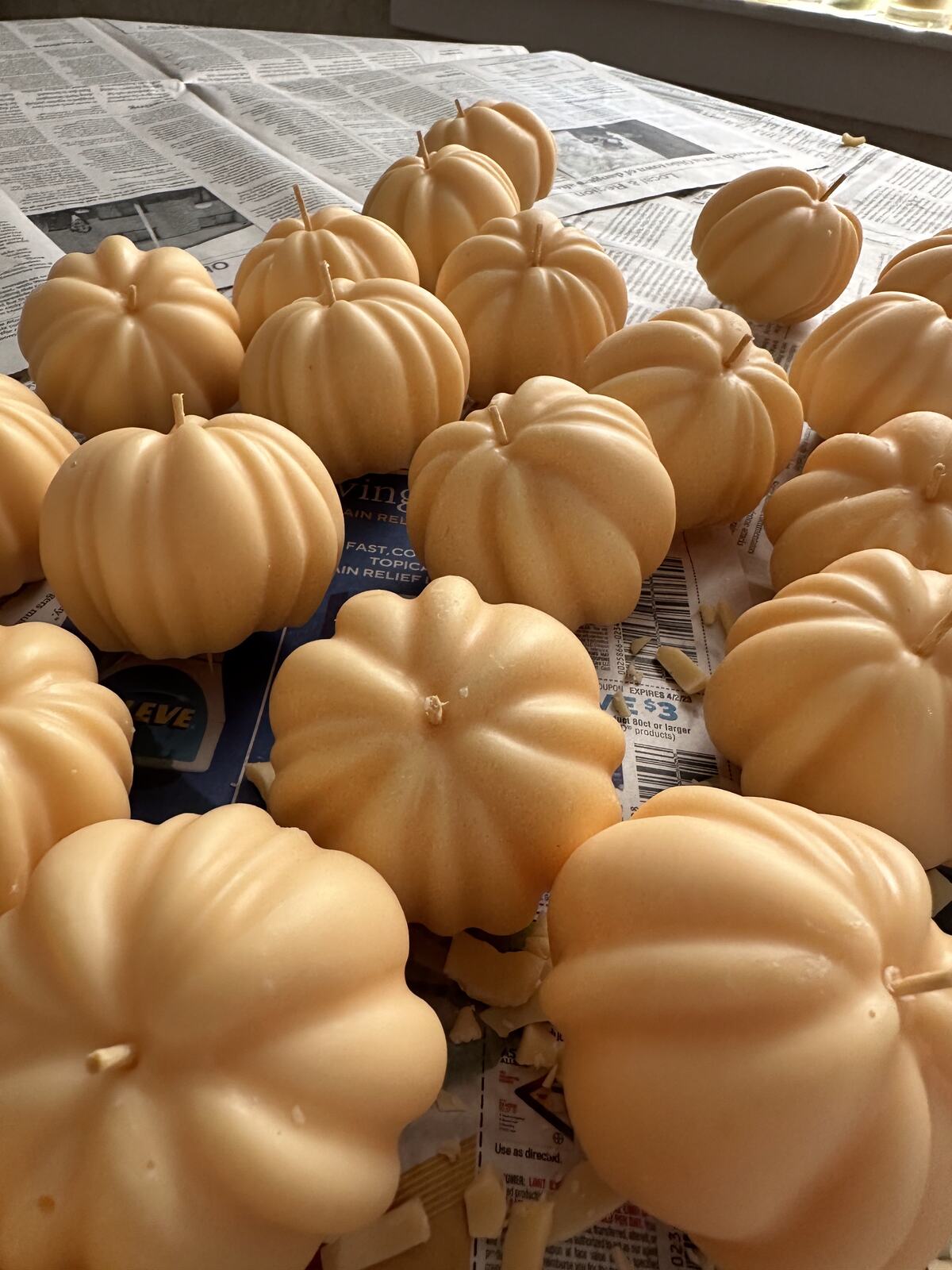 A batch of cream pumpkin-shaped wax pours drying on paper